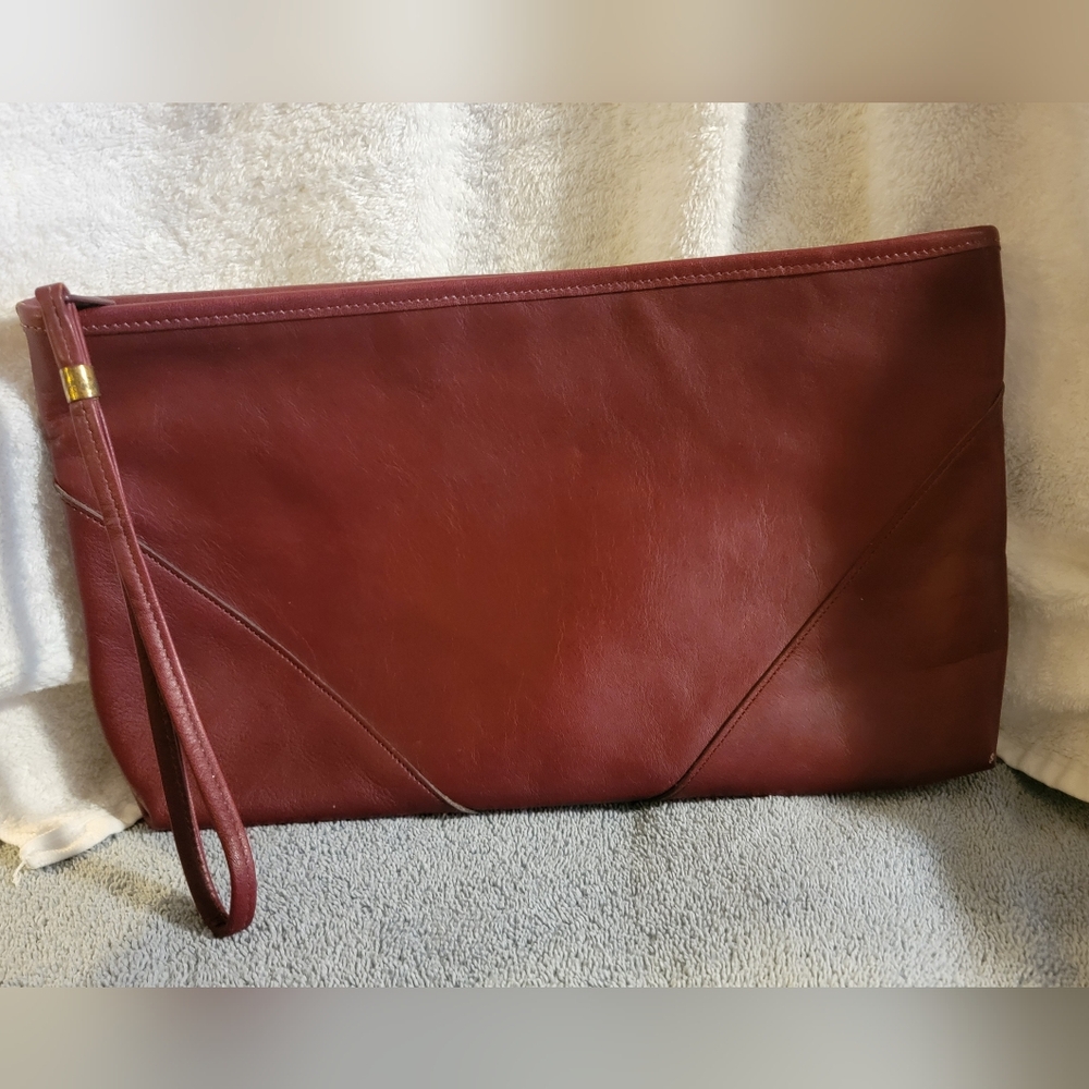 Stylish maroon clutch purse. Has a wristlet strap. Zipper closure